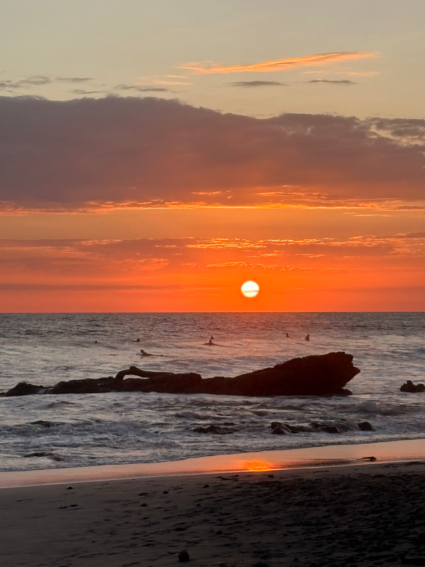 Sunset over the ocean at Santa Teresa, Costa Rica, with rocks silhouetted in the surf